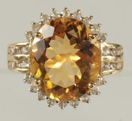 A 9CT YELLOW GOLD RING SET WITH A LARGE OVAL CITRINE AND SEVERAL RBC WHITE TOPAZ. Citrine 6.48ct.