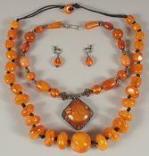 TWO AMBER RESIN BERBER NECKLACES AND A PAIR OF EARRINGS.