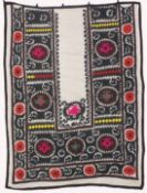 AN UZBEK SUZANI EMBROIDERED TEXTILE, with floral motifs and decorative roundels in pink, red, green,