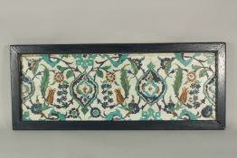 THREE ISLAMIC GLAZED POTTERY FLORAL TILES UNITED IN A WOODEN FRAME, 33cm x 82cm overall.