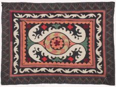 AN UZBEK SUZANI EMBROIDERED TEXTILE, with central foliate motif in orange, green, maroon, red, and