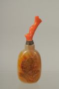 A CHINESE AGATE SNUFF BOTTLE WITH CORAL STOPPER, the bottle carved with carp, 11.5cm high overall.