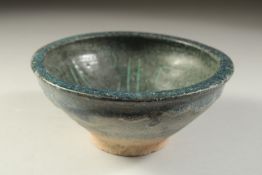A 12TH CENTURY NISHAPUR GLAZED POTTERY BOWL, the interior with calligraphy, 19cm diameter.