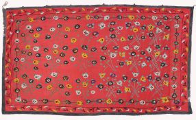 AN UZBEK SUZANI EMBROIDERED TEXTILE, with floral decoration on red ground, 325cm x 224cm.