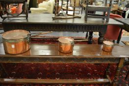 A good graduated set of three copper saucepans with matching lids.