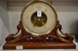 A Victorian aneroid barometer by Baker of London, mounted on a carved oak support.