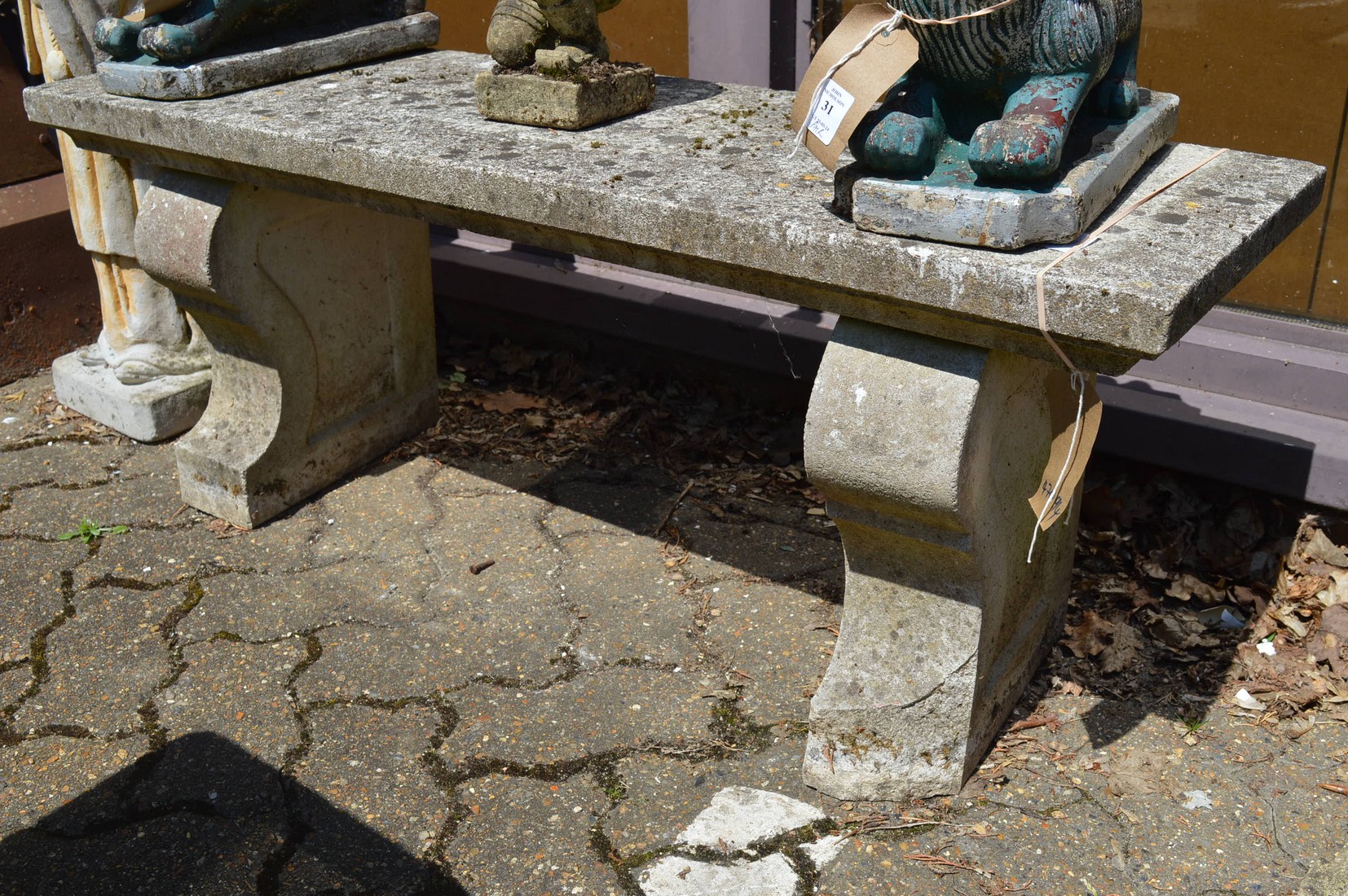 A reconstituted stone rectangular garden bench with curving supports.