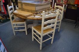 A pine circular extending dining table with one leaf on a painted base together with four painted