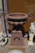 A good large pair of cast iron twin handled garden urns on separate tapering square bases.