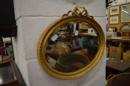A gilt framed oval wall mirror.