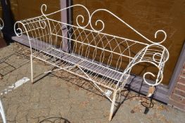 A white painted wrought iron and wire work scroll-end garden bench.