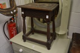 A carved oak joint stool with hinged storage compartment.