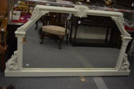 A large green painted overmantle mirror with carved decoration.
