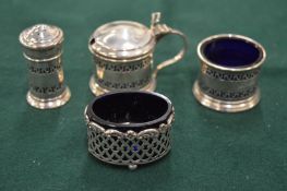 A set of three silver condiments and another similar salt.
