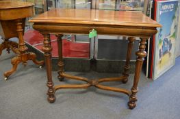 A walnut single drawer side table with turned legs united by an X shaped stretcher.