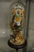 A floral and shell display housed under a glass dome.
