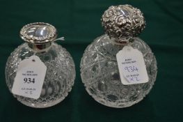 Two cut glass scent bottles with hinged silver tops.