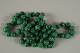 A STRING OF EIGHTY-TWO MALACHITE BEADS. 90cms long.