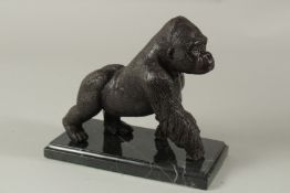 A BRONZE GORILLA on a marble base. 14cms high.