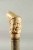 A WALKING STICK with a carved bone handle of the head of a man.