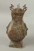 AN ARCHAIC BRONZE TWO-HANDLED VASE AND COVER with ring handles. 28cms high.