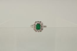 AN 18ct WHITE GOLD, EMERALD AND DIAMOND CLUSTER RING.