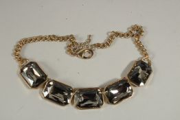 A GILT NECKLACE set with five grey cut stones.