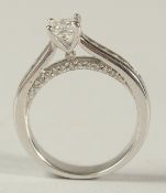 A 14ct WHITE GOLD PRINCESS CUT DIAMOND SOLITAIRE RING with RBC diamond shoulders and bridge.