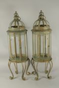 A LARGE PAIR OF GREEN METAL GLAZED LANTERNS on four curving legs. 80cms high.