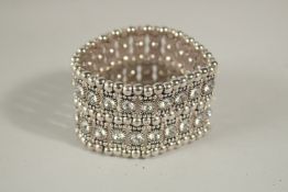 A WIDE DIAMANTE BRACELET in a white silk bag.