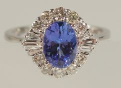 AN 18ct WHITE GOLD OVAL TANZANITE AND DIAMOND CLUSTER RING. Tanzanite 1.34ct. RBC and tapered