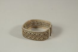A CHINESE PIERCED WHITE METAL BANGLE.