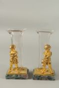 A GOOD PAIR OF GILT AND GLASS CUPID VASES on Blue John bases. 23cms high.