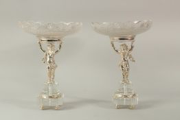 A VERY GOOD PAIR OF SILVER PLATE CUPID TAZZAS with cut glass bowls. 34cms high x 24cms diameter.