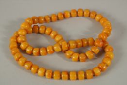 A STRING OF SIXTY-EIGHT BUTTERSCOTCH AMBER BEADS. 66cms long.