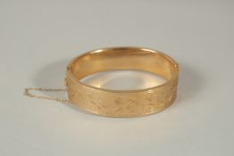 A 9ct GOLD ENGRAVED BANGLE. 24grms.