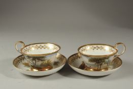 A PAIR OF ENGLISH PORCELAIN CUPS AND SAUCERS painted with classical lake scenes.