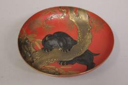 A VERY FINE 19TH CENTURY JAPANESE MEIJI RED AND GILT LACQUER SAKE DISH, depicting a bear behind a