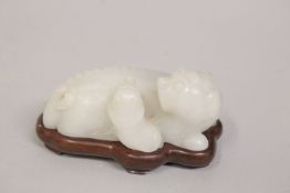 A CHINESE CARVED JADE FOO DOG, with fitted wooden stand, 8cm long.