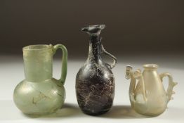 A COLLECTION OF THREE ROMAN OR EARLY ISLAMIC BLOWN GLASS EWERS / VESSELS, tallest 16cm (3).