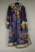 A CHINESE EMBROIDERED BLUE SILK ROBE, adorned with threaded floral sprays and panels of figures.