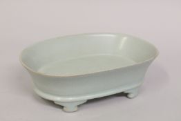 A CHINESE CELADON GLAZE OVAL SHAPE PLANTER, with incised characters to the base and raised on four