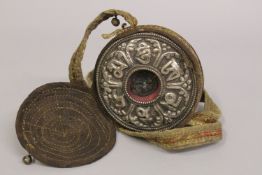 A TIBETAN EMBOSSED WHITE METAL PORTABLE BUDDHISTIC SHRINE.