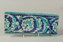 A FINE 16TH CENTURY OTTOMAN IZNIK GLAZED POTTERY BORDER TILE, 29cm x 12cm.