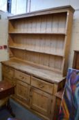 A large pine dresser with delft rack, the base with three drawers and three cupboard doors 225cm