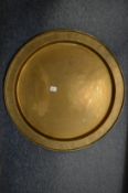 A large circular brass dish with engraved border.