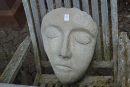 A reconstituted stone garden ornament modelled as a face.