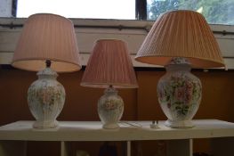 Three large floral decorated pottery lamps.
