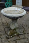 Reconstituted stone bird bath with dolphin supports.