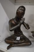 A bronze model of a seated flute player.